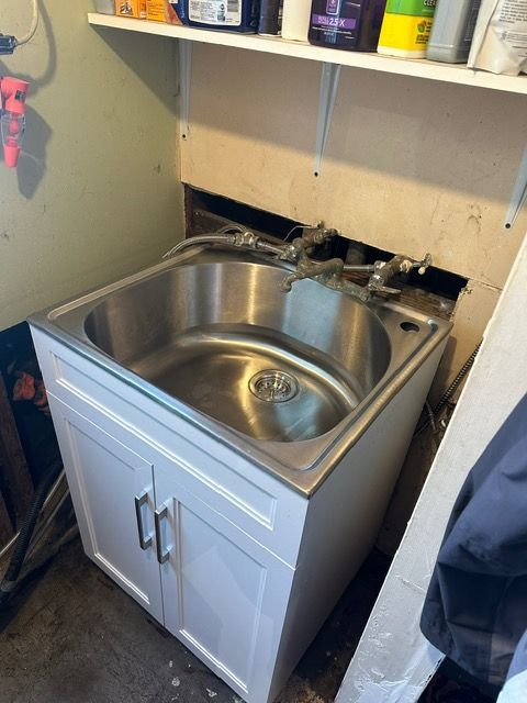 A stainless steel sink in a laundry room