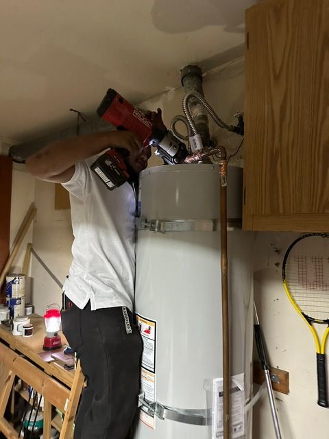 A man is working on a water heater in a kitchen