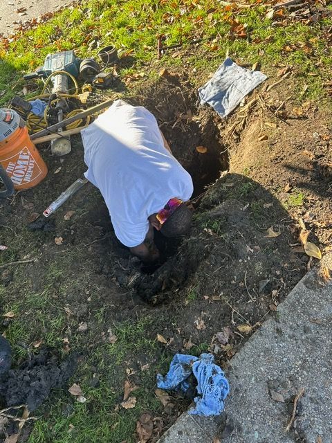 A man is digging a hole in the ground next to a home depot bucket.