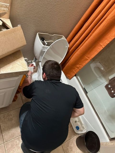 A man is fixing a toilet in a bathroom