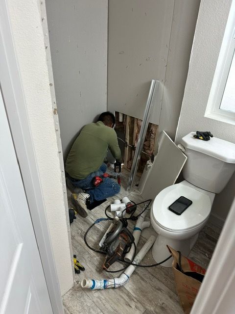 A man is working on a toilet in a bathroom.