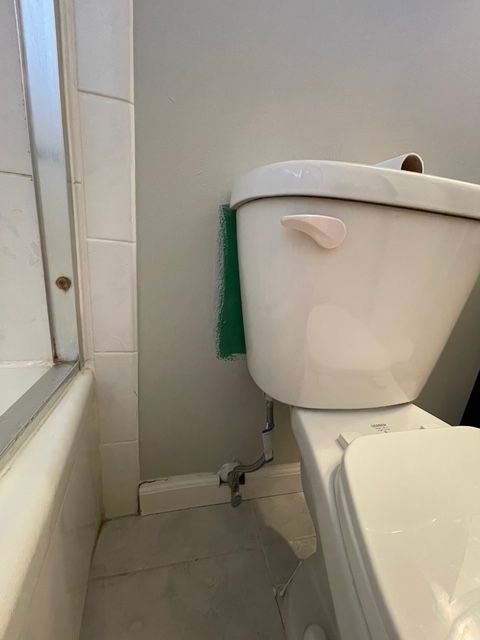 A white toilet is sitting in a bathroom next to a bathtub.