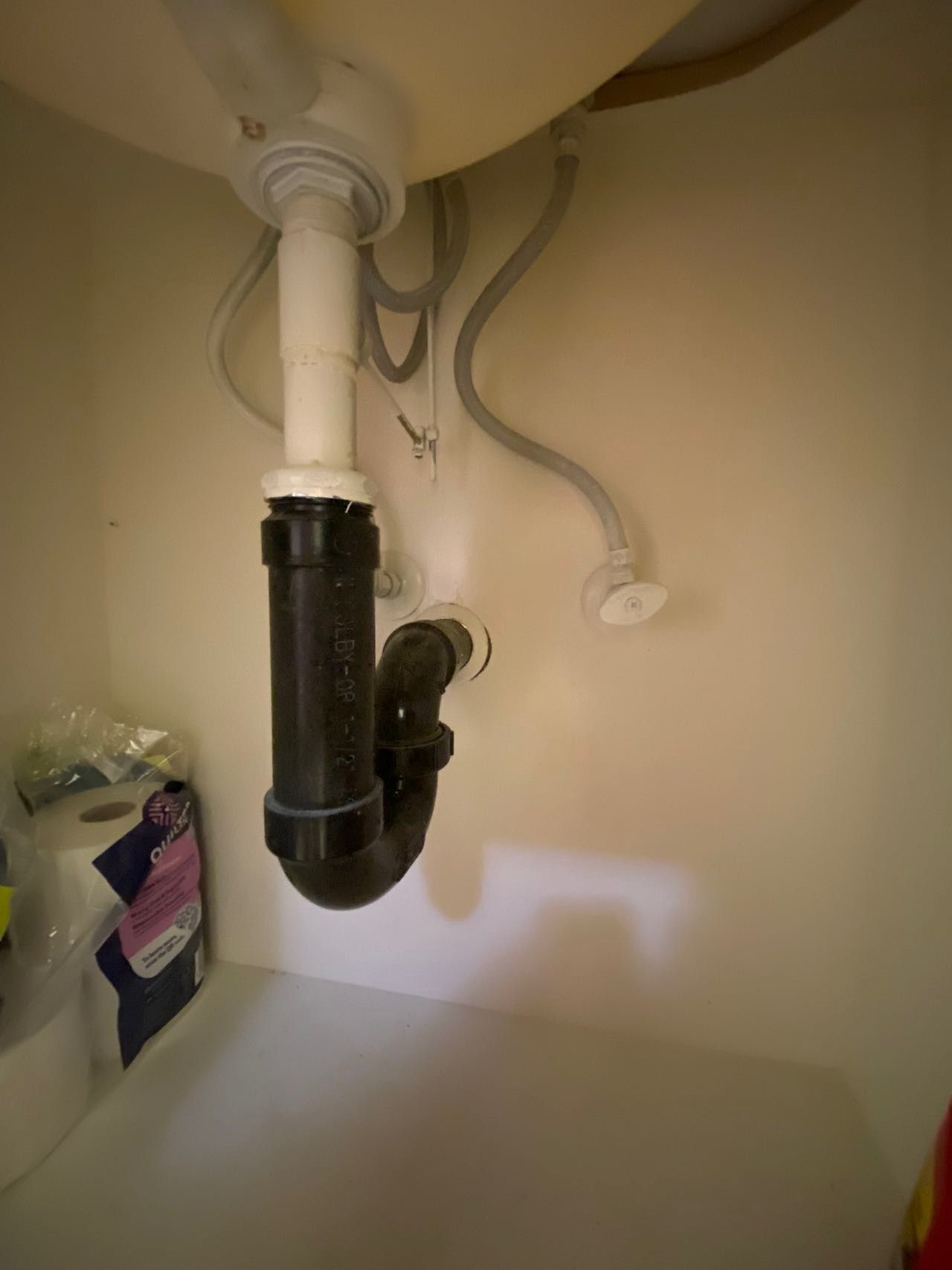 A bathroom sink with a black pipe underneath it