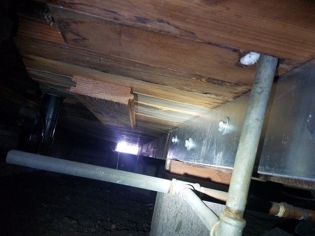 A wooden floor with a metal pipe underneath it