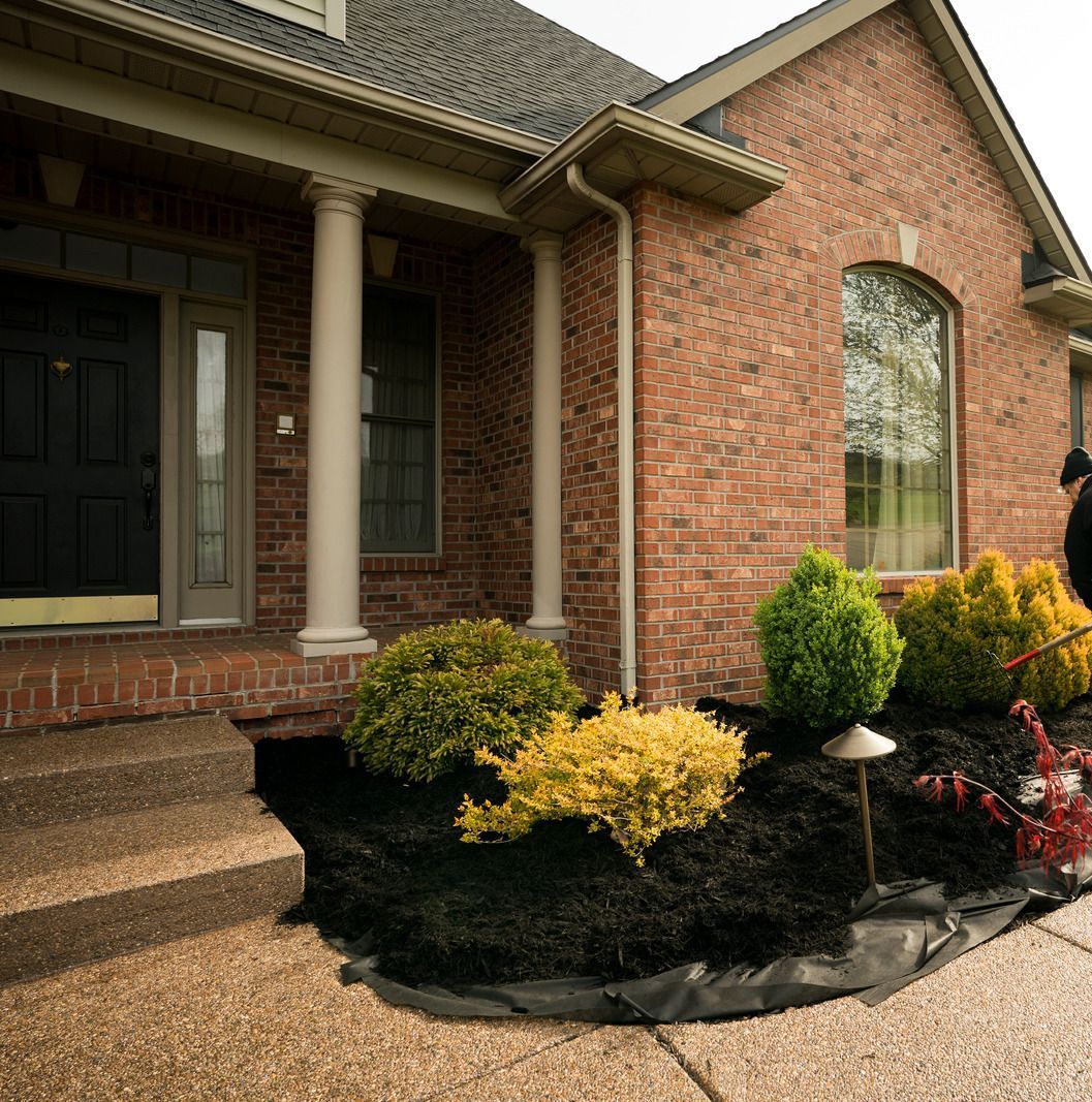A brick house with a lush green garden in front of it