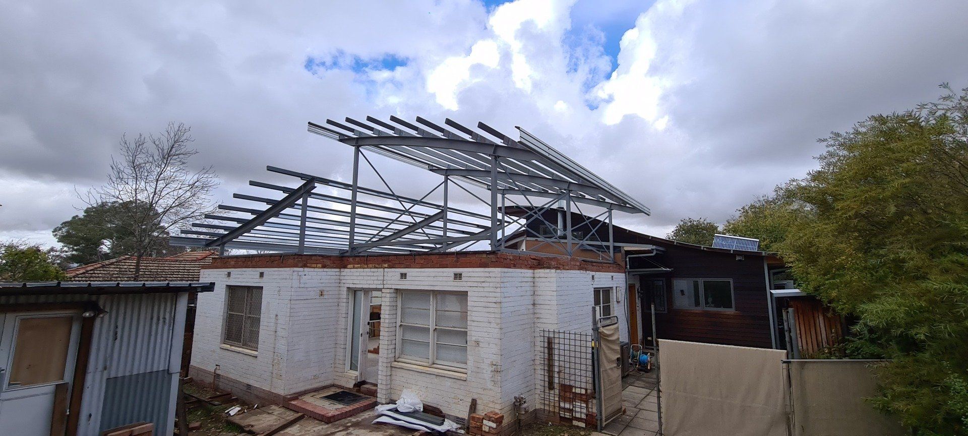 A house with a roof that is being built on a cloudy day.
