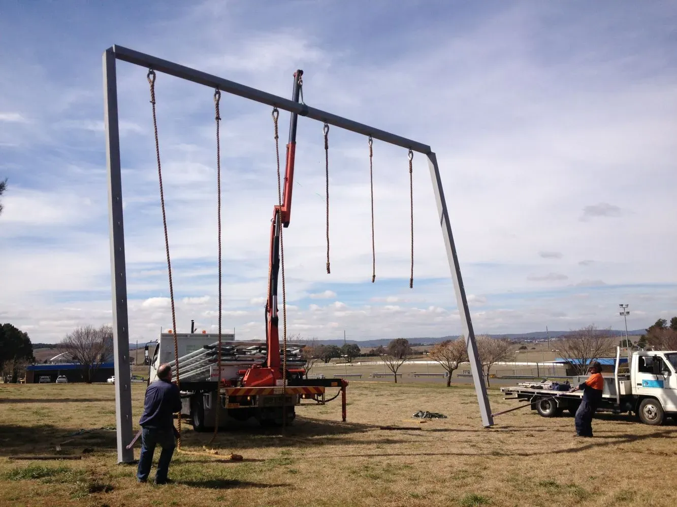 A crane is lifting a swing set in a field