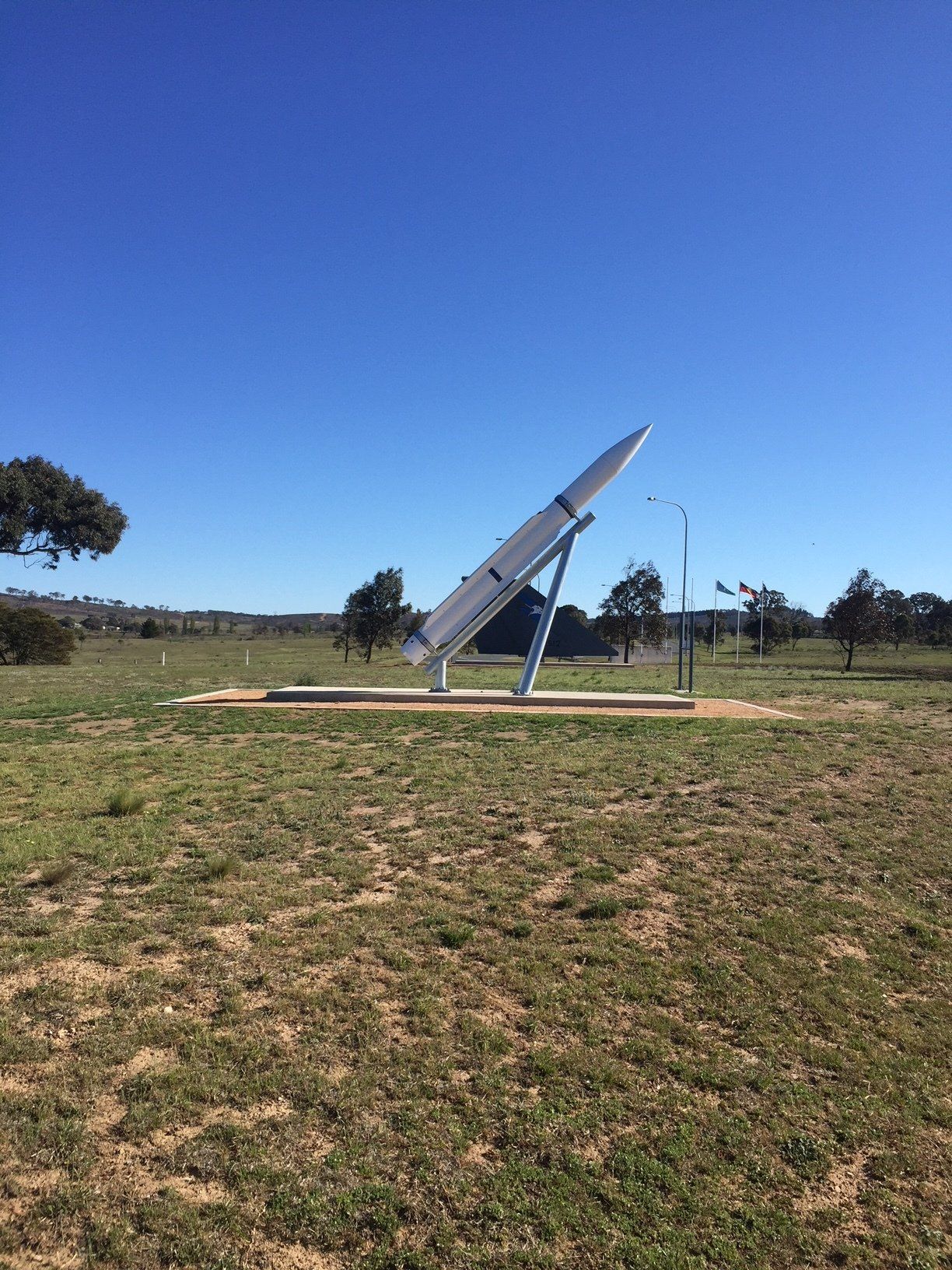 A large rocket is sitting in the middle of a grassy field.