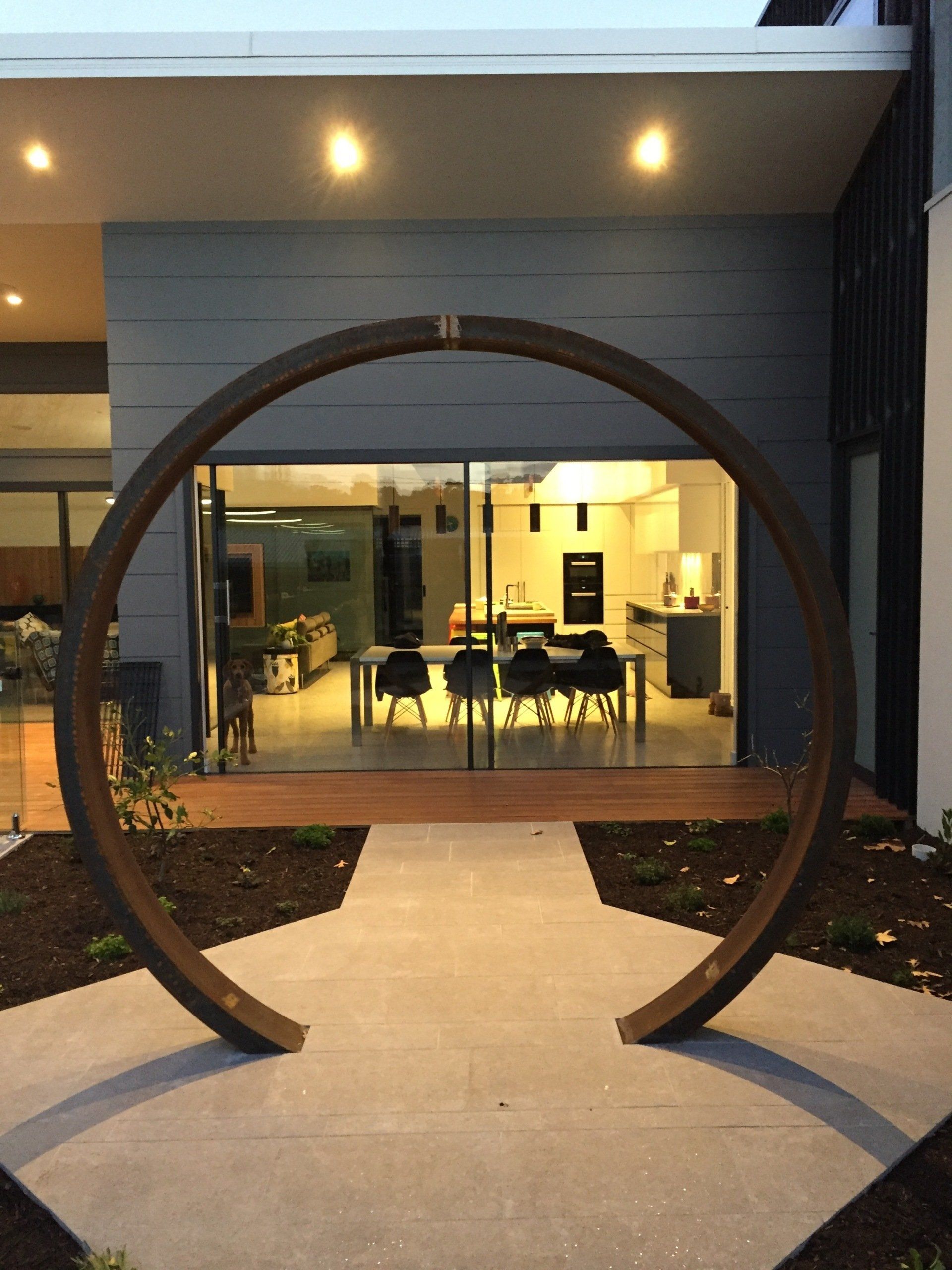 A house with a large circular sculpture in front of it