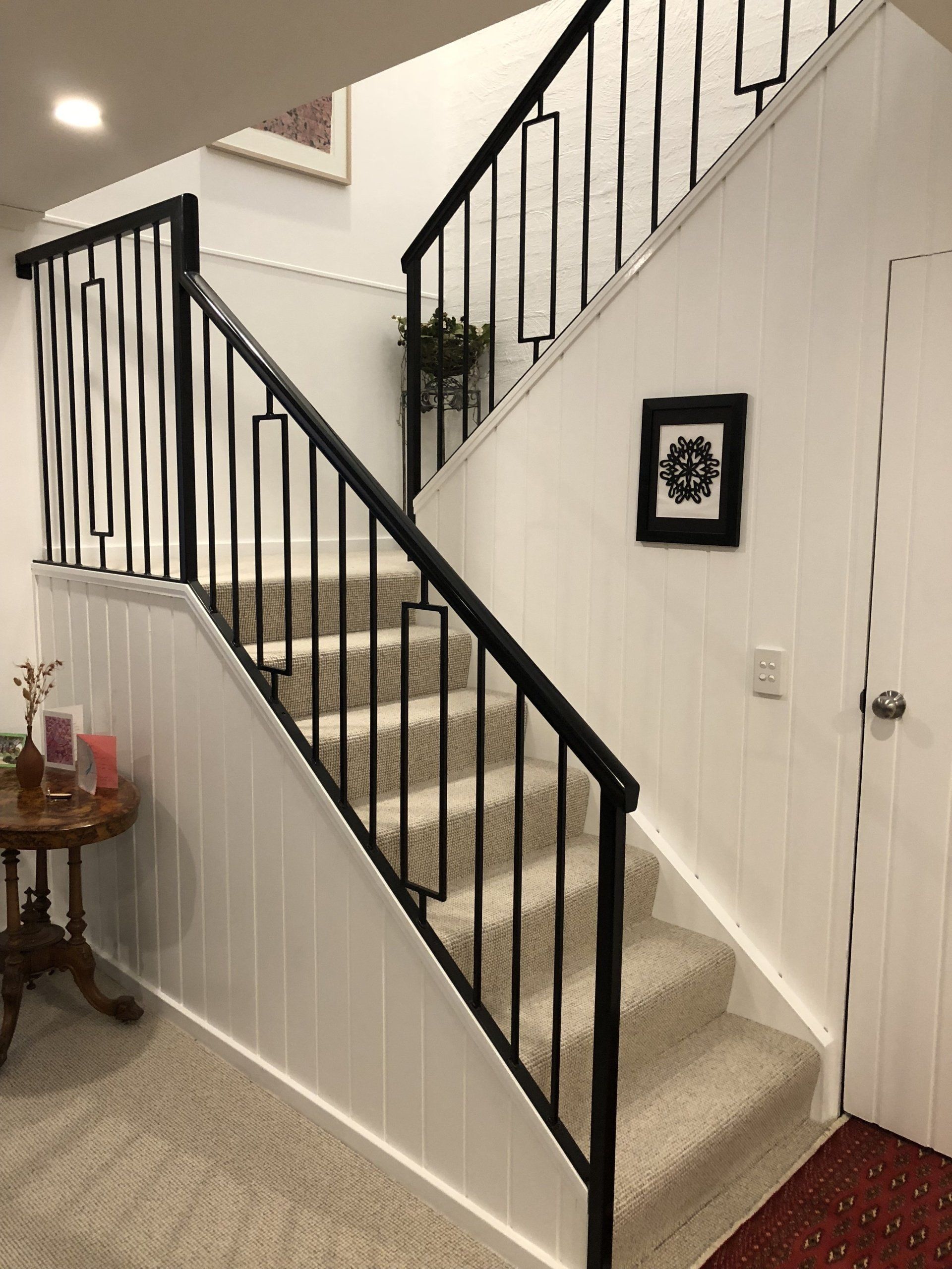 A staircase with a black railing and a picture on the wall.