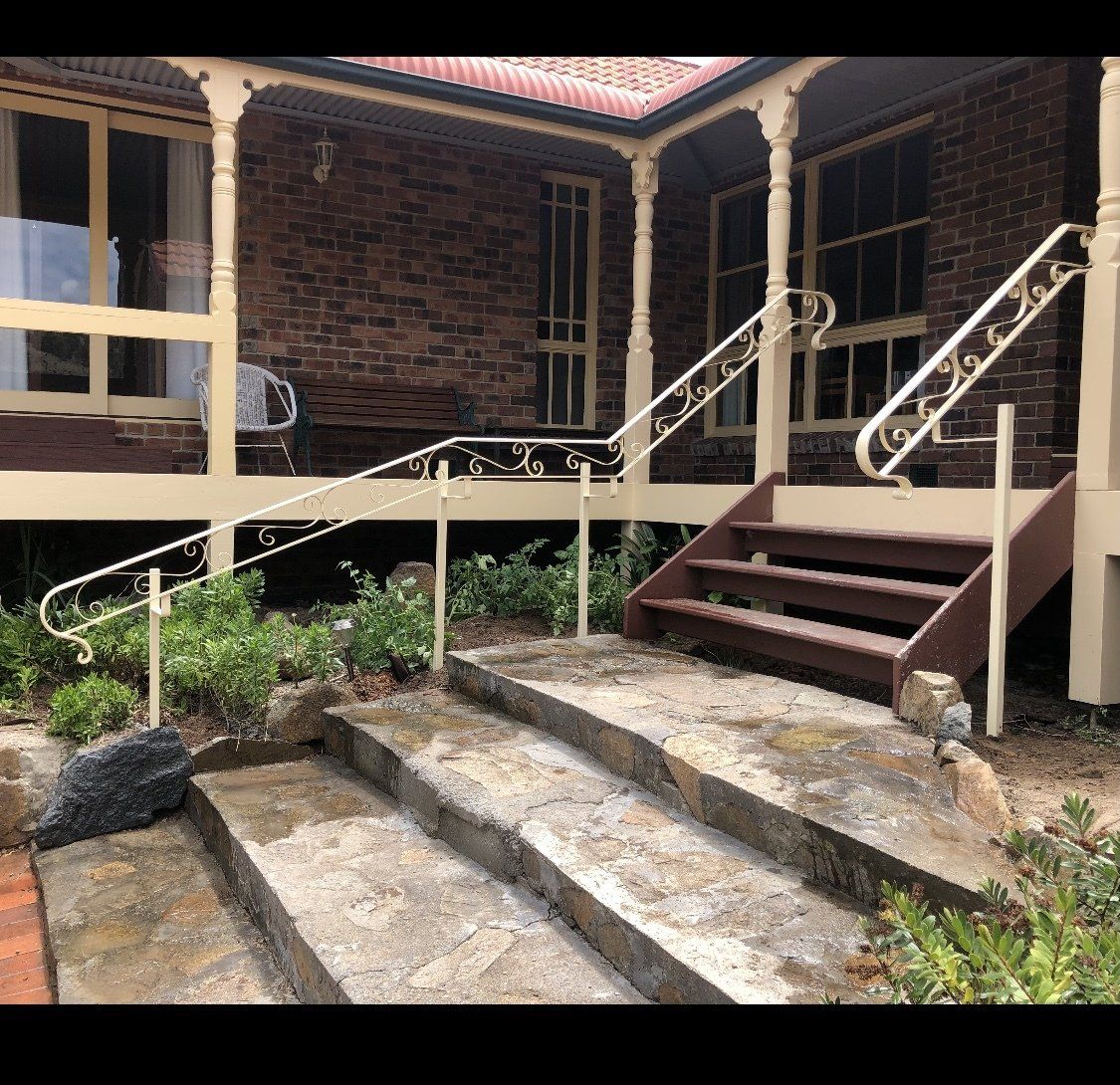 A brick house with stairs leading up to it and a porch.