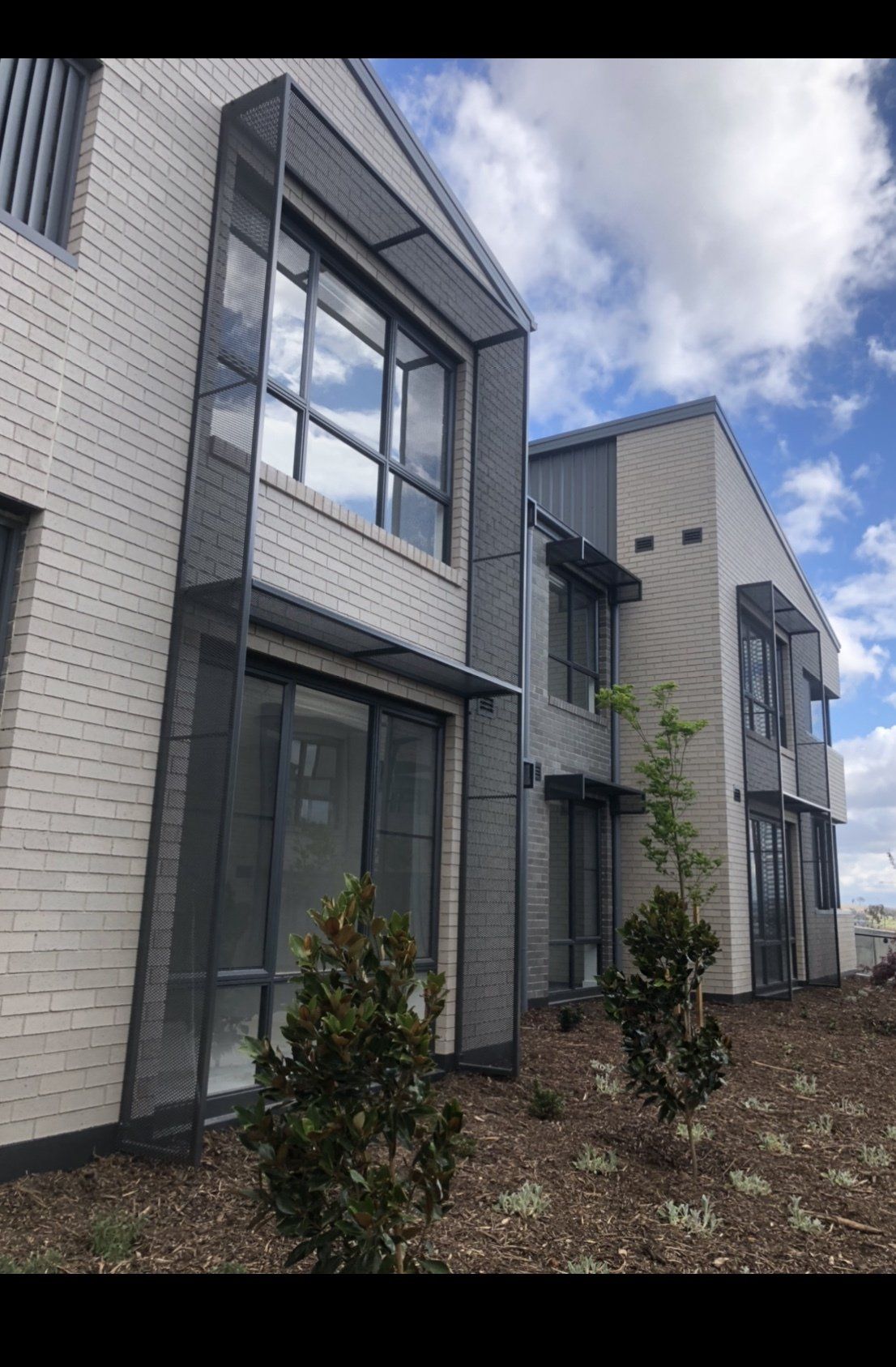 A large white brick building with lots of windows and trees in front of it.