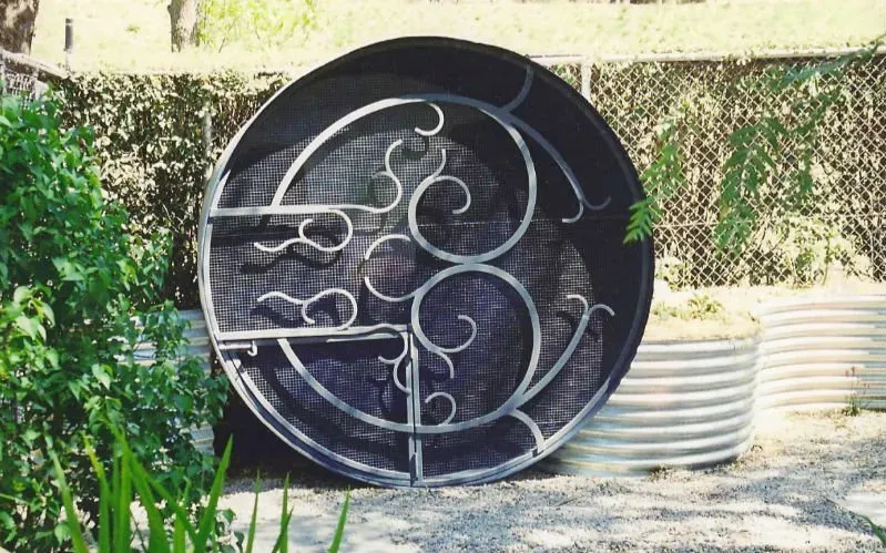 A large metal object is sitting on the ground in a garden.