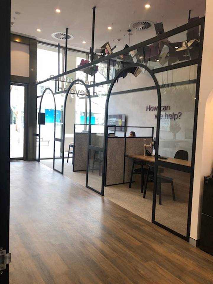 A room with cubicles and a sign that says `` how can we help ? ''