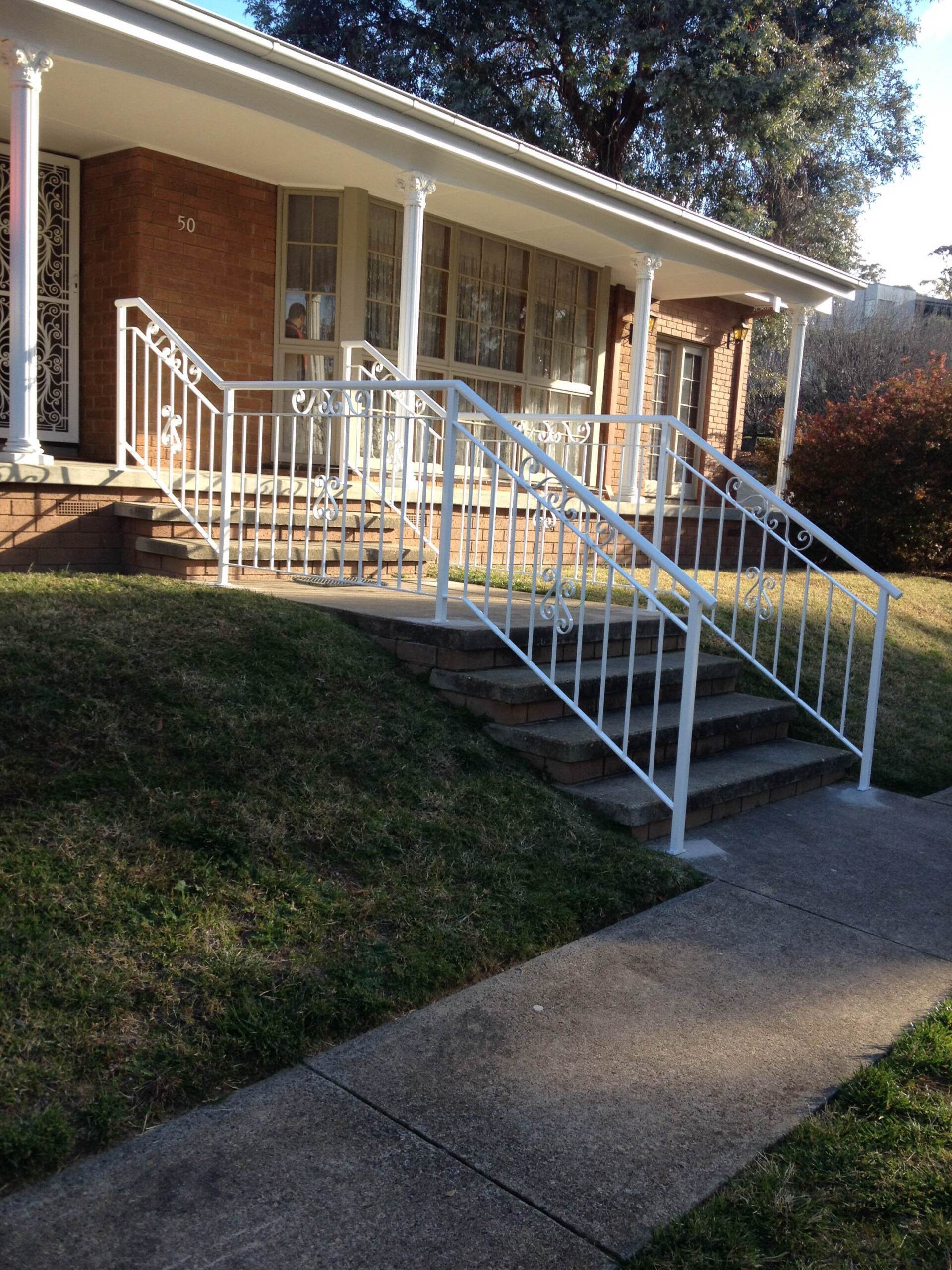 A brick house with a white railing and stairs