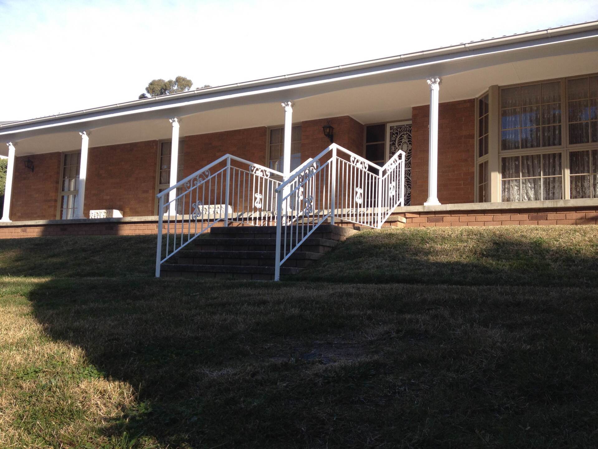 A brick house with a white railing and stairs