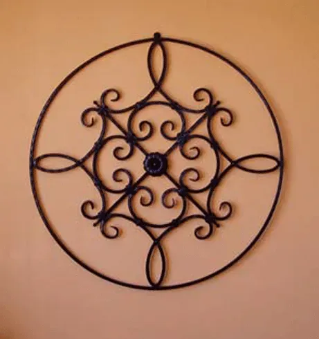 A wrought iron circular design is hanging on a wall