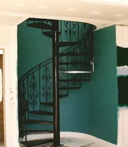 A spiral staircase in a room with green walls
