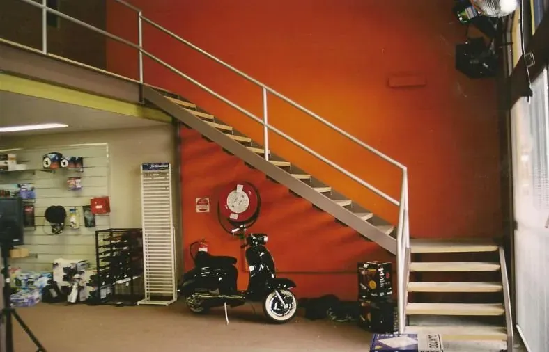 A motorcycle is parked under a staircase in a store