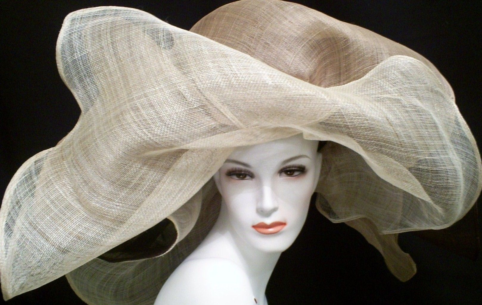 Mannequin head wearing a large, tan woven hat with a flowing brim.
