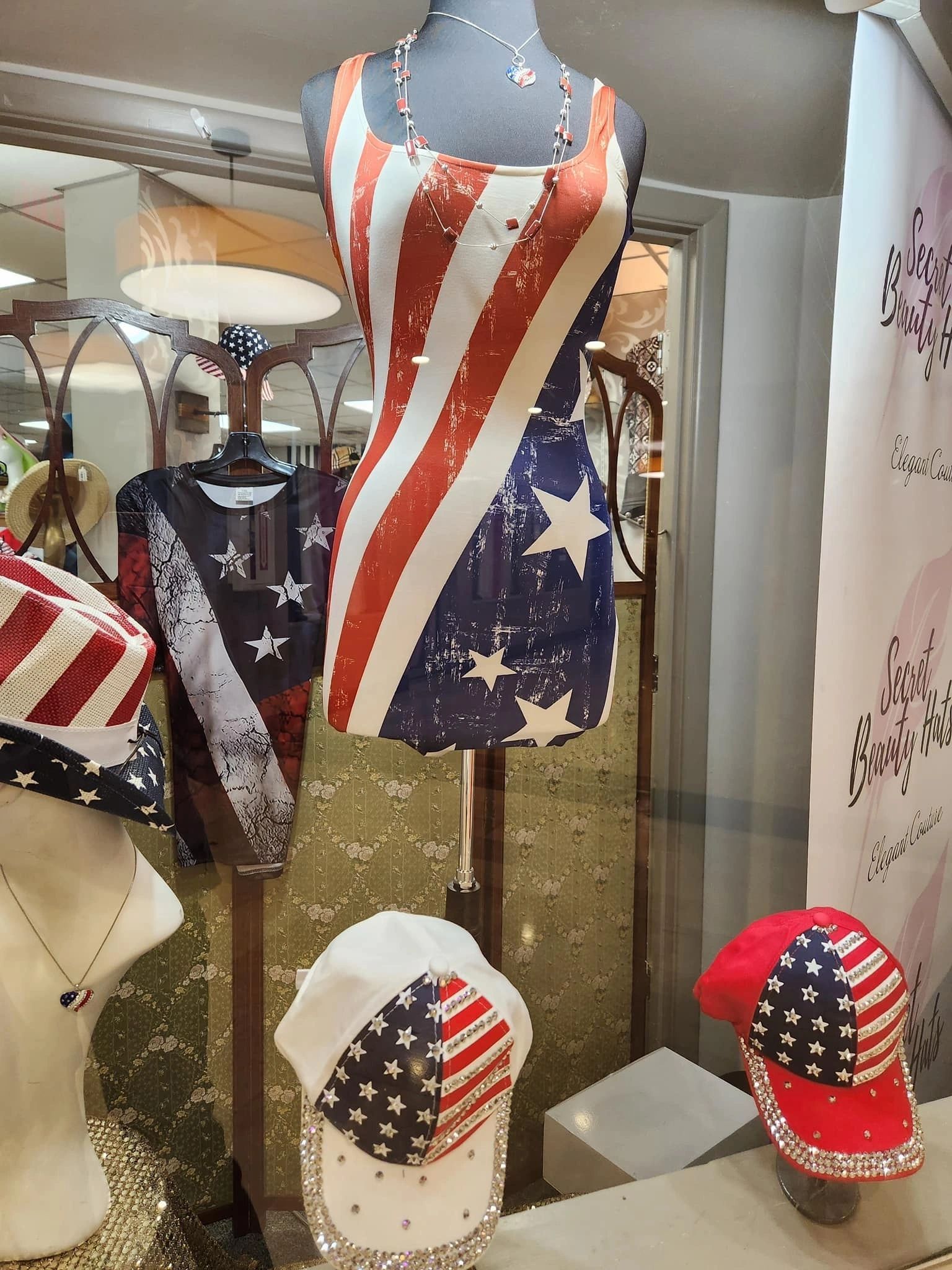 American flag-themed clothing display: dress, caps, and accessories in a store window. Red, white, and blue colors.