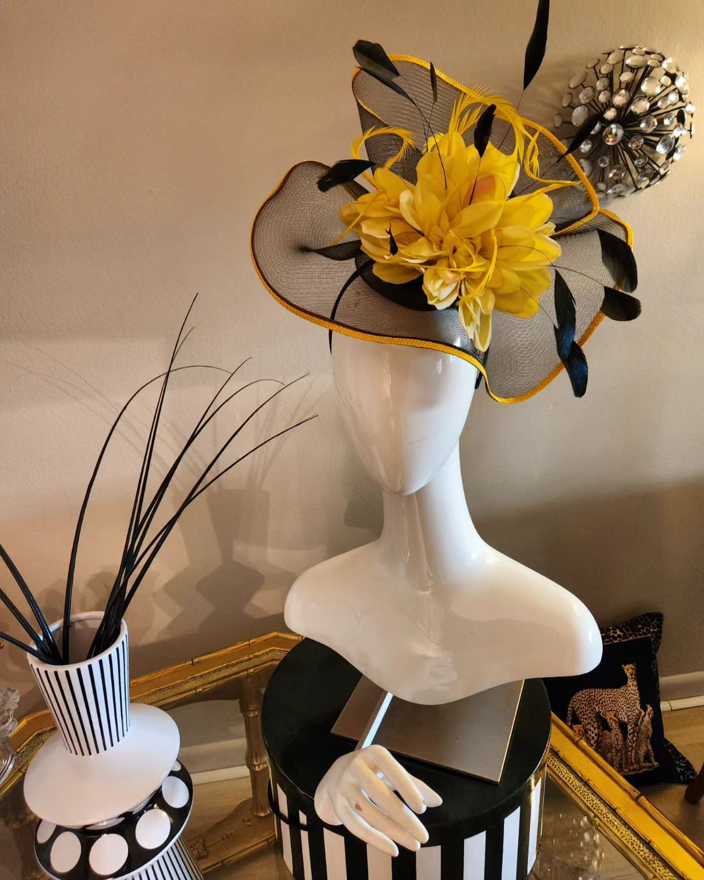 White mannequin head with elaborate yellow and black hat display.