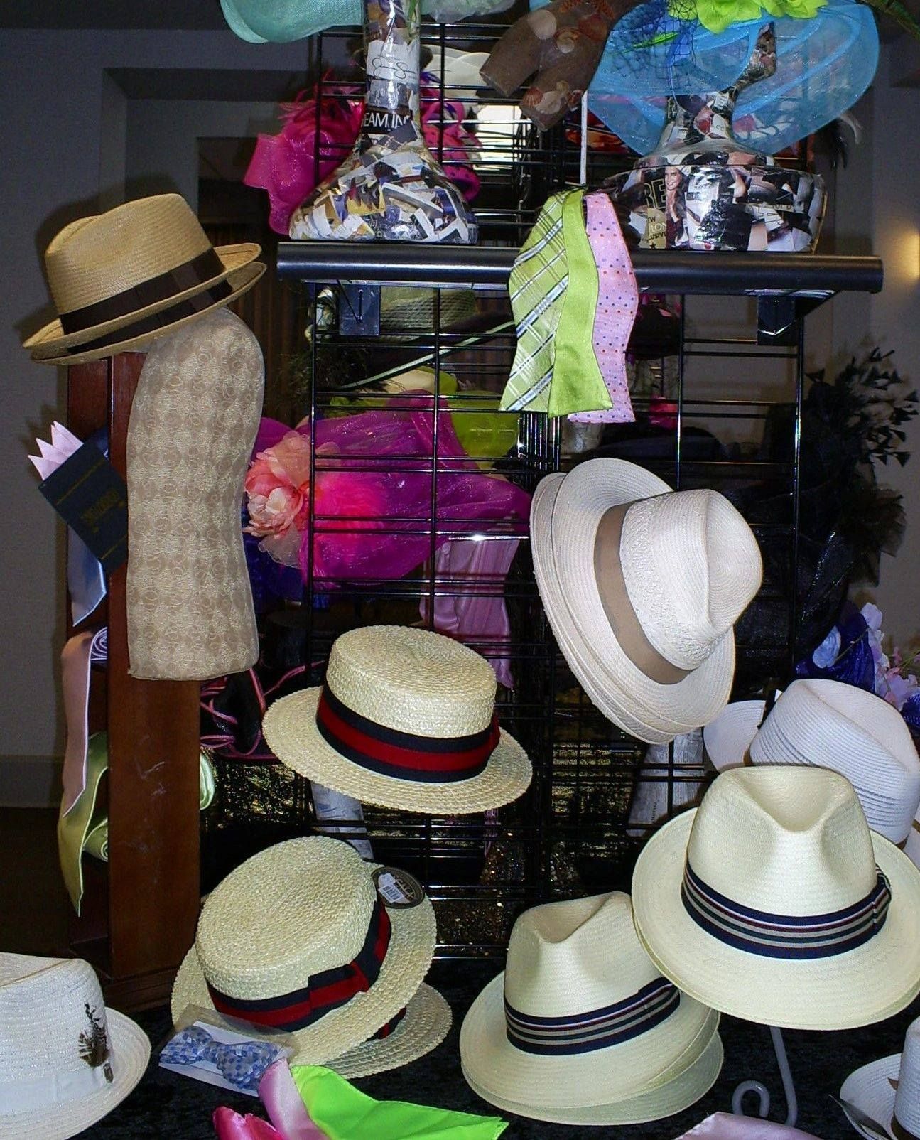 Display of various hats, including fedoras and straw hats, on a black wire rack.