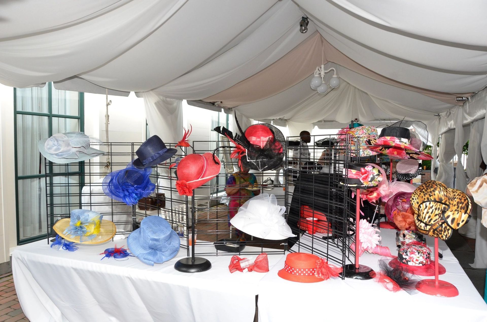 Hats displayed on a white table under a white tent. Various colors and styles are visible.