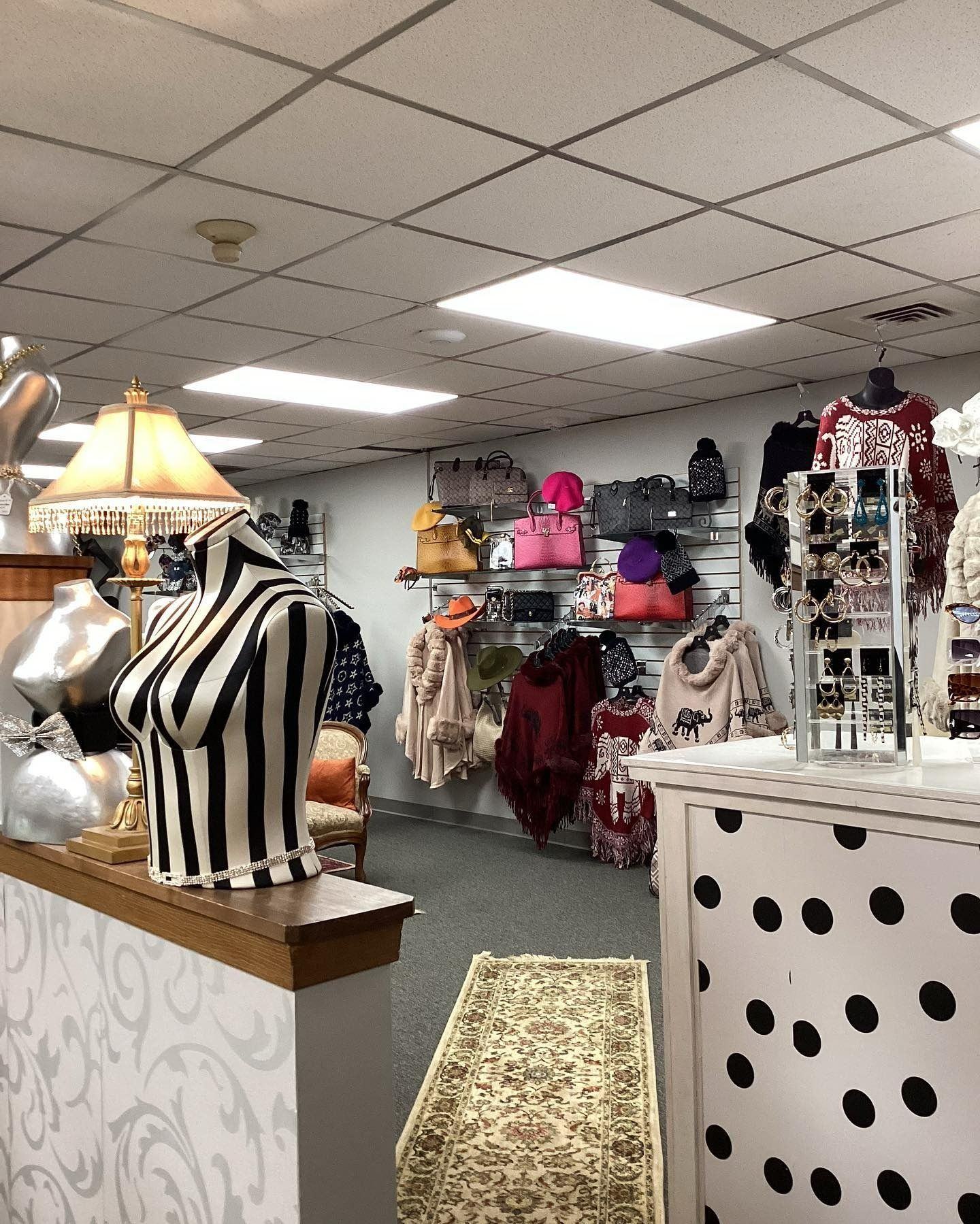 Clothing store interior with clothing racks, purses, jewelry, and mannequins.