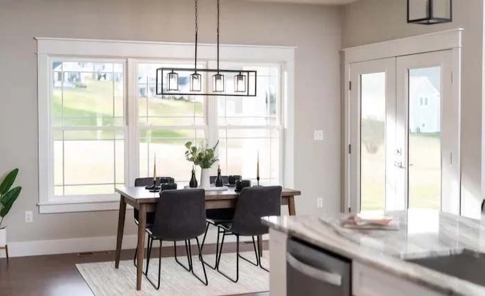 Dining room with table set for four, large window, black light fixture, and door.