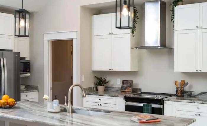 Bright kitchen with white cabinets, stainless steel appliances, and a marble countertop.