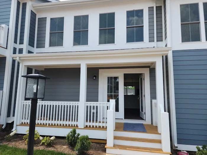 Blue and white townhouse exterior with porch and open double doors.