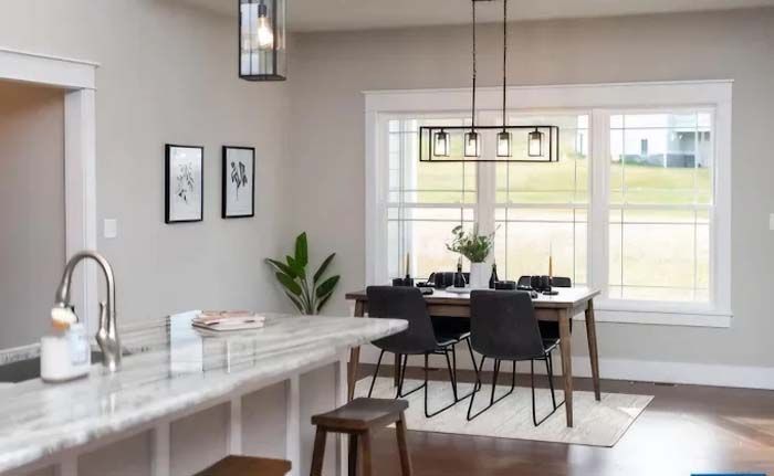 Dining room with table, chairs, and overhead lighting. Window with view, neutral tones.