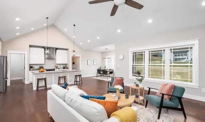 Open-concept living space with kitchen, seating area, and dining, with hardwood floors and bright lighting.