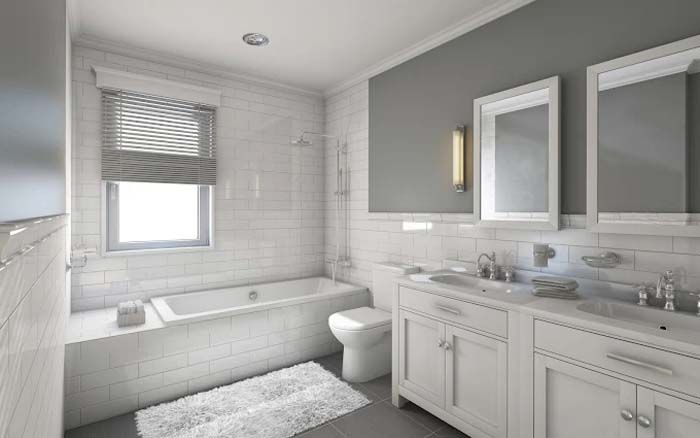 White tiled bathroom with tub, double vanity, toilet, and window with blinds.