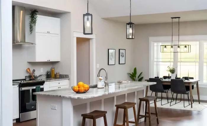 Kitchen with island, stools, white cabinets, and dining area with table and chairs.