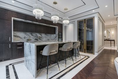 Modern luxury kitchen with marble island, black cabinetry, and pendant lights