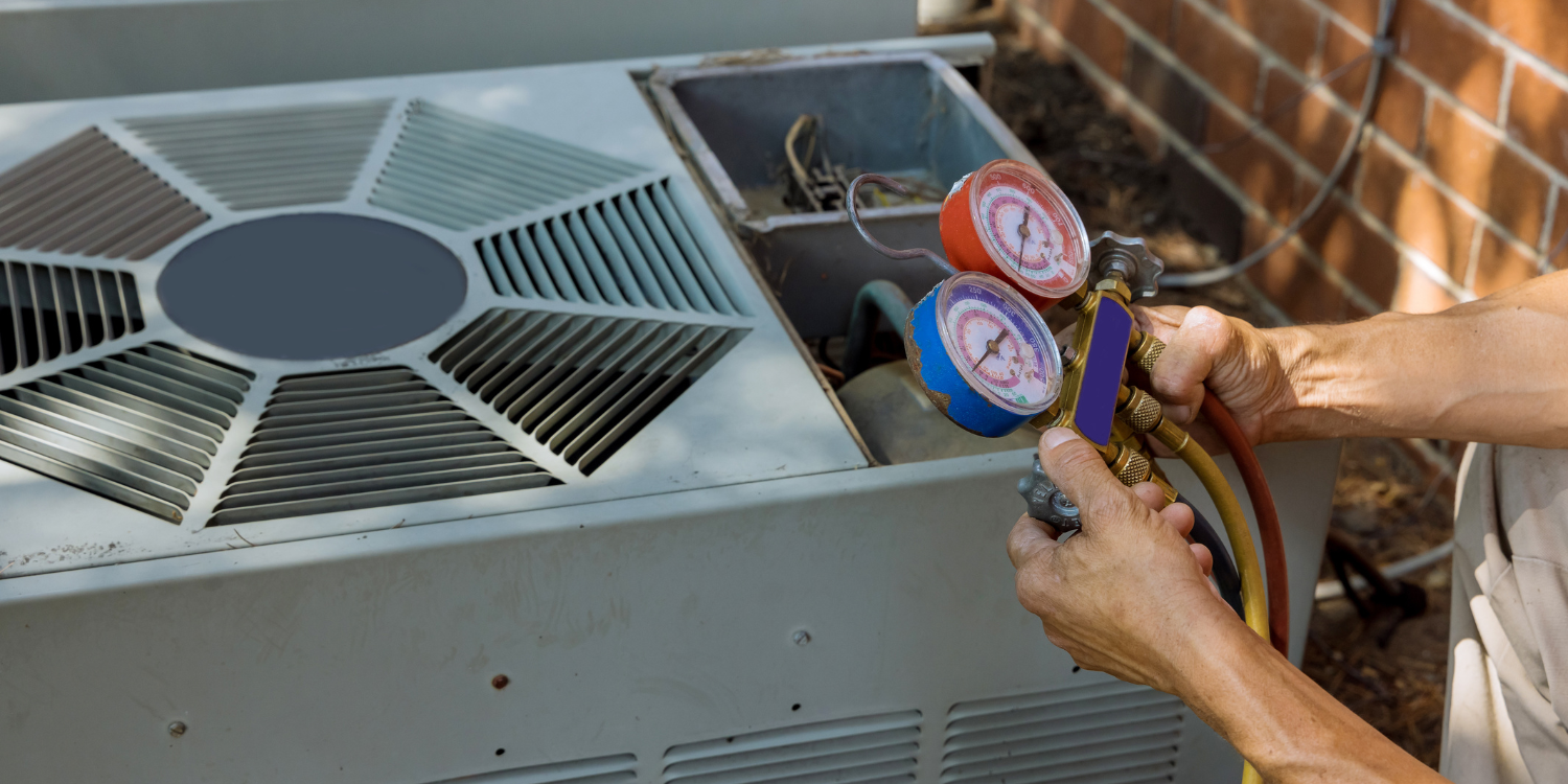 Hands checking HVAC unit gauges and hoses beside a metal air conditioner.