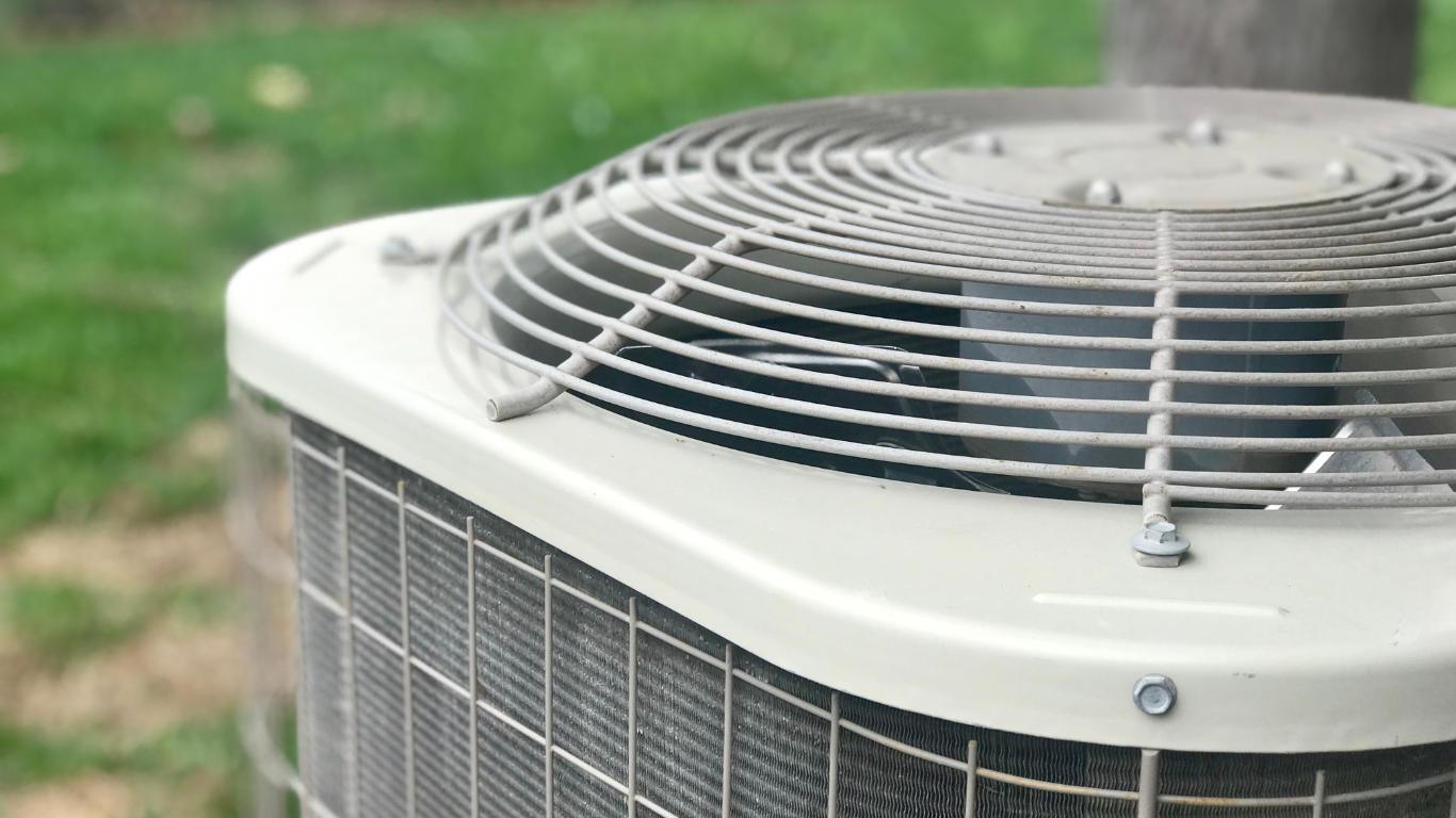 Outdoor air conditioner unit with circular fan grille on top and gray metal sides