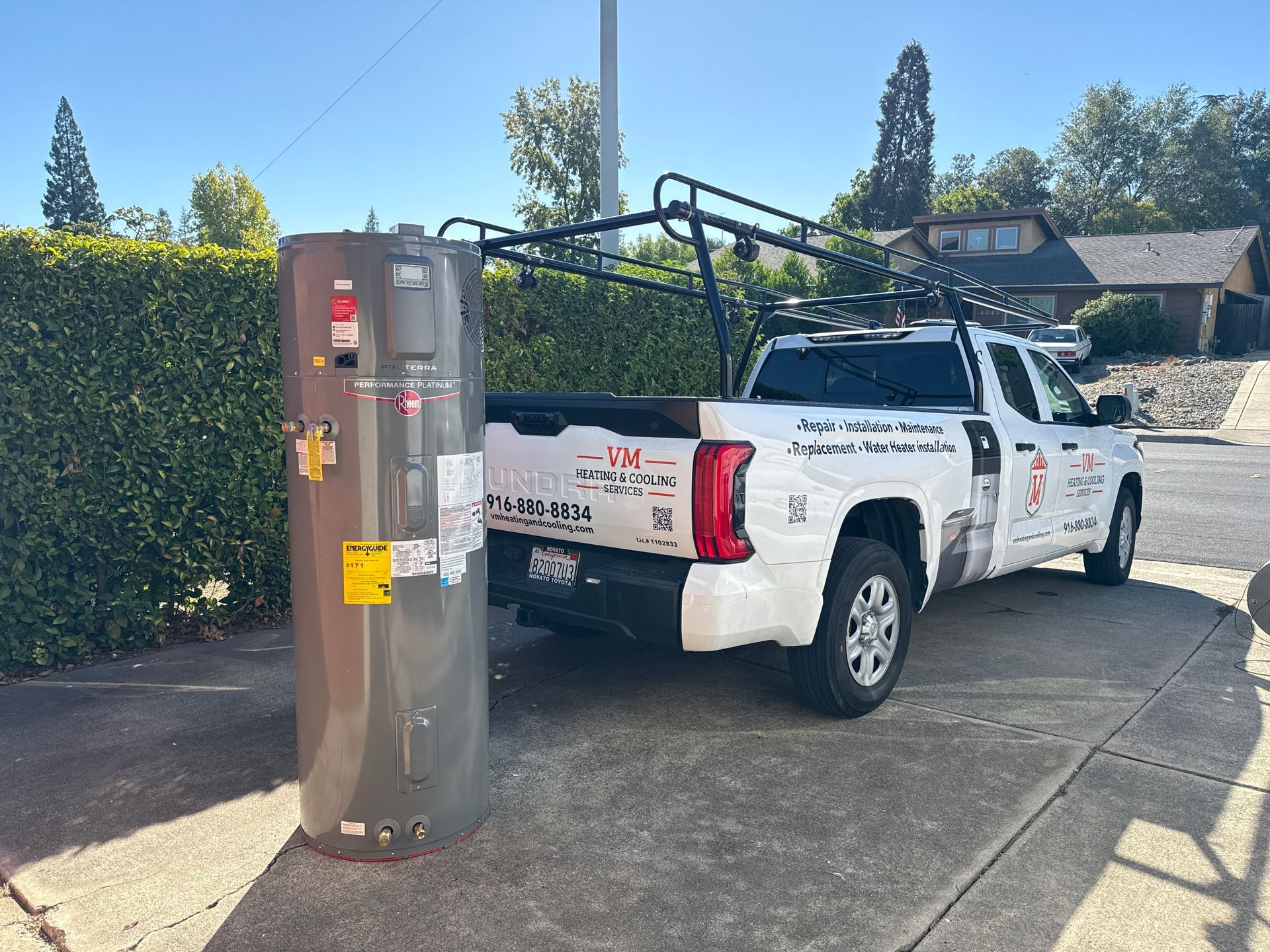 White utility pickup parked beside a tall roadside emergency call box on a sunny driveway.