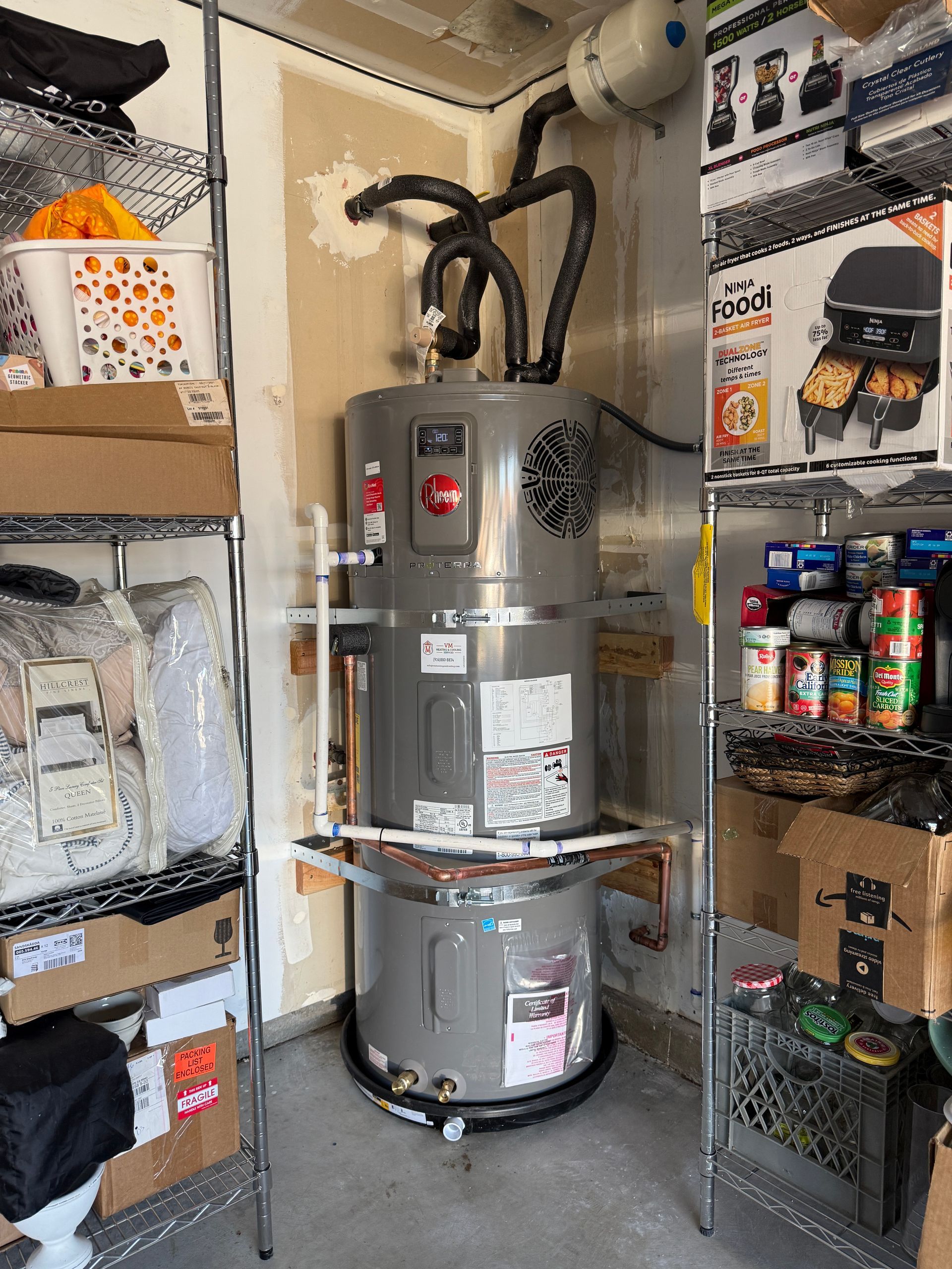 Utility room with a large silver water heater, shelves of supplies, and storage bins.