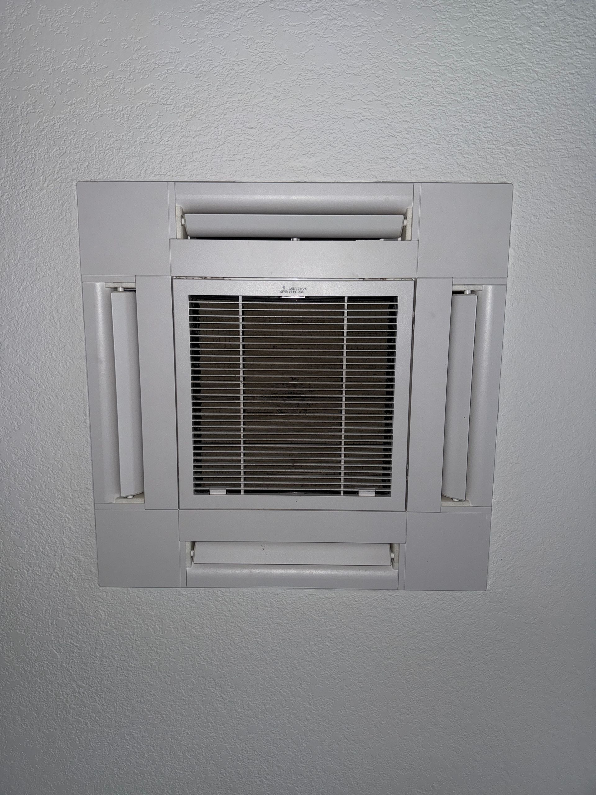 Square ceiling vent with a central filter grille and narrow side vents on a gray ceiling