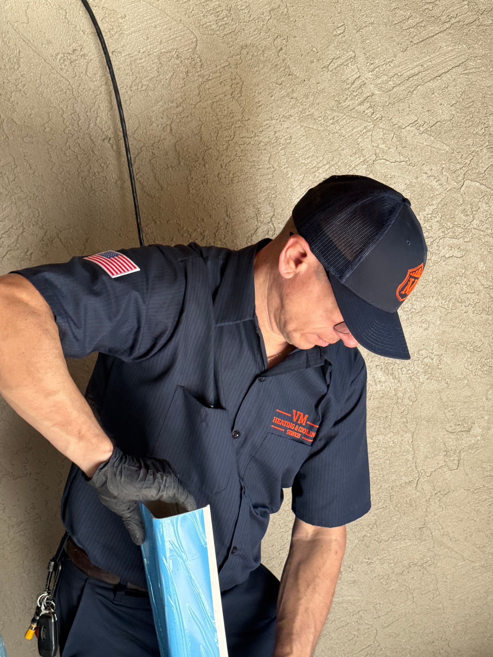 Worker in dark uniform and cap handling a blue package indoors
