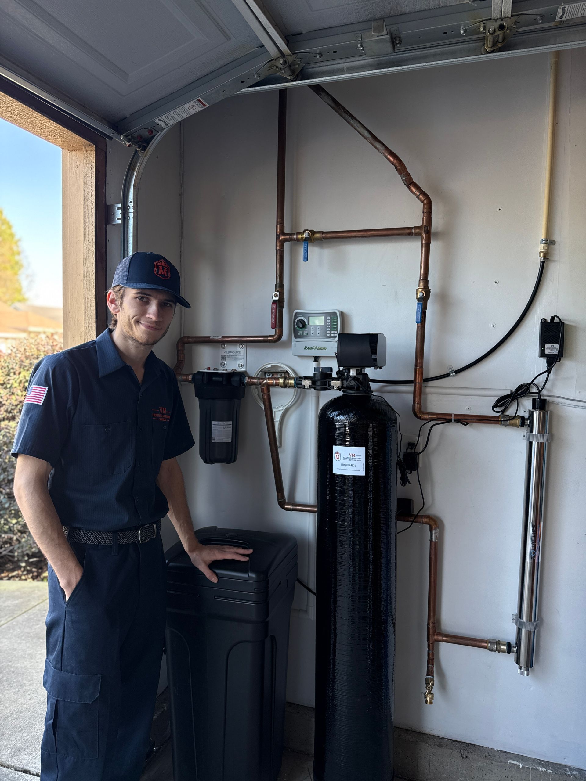 Technician standing beside industrial tanks and piping in a garage utility area