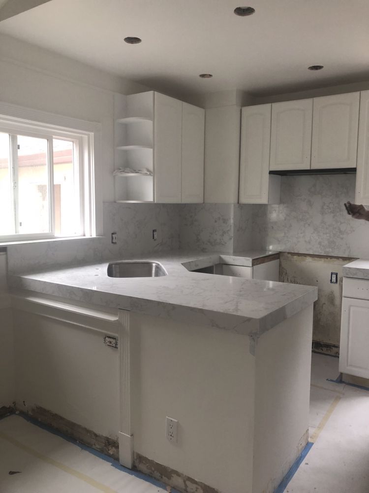 White kitchen under renovation with new countertops, cabinets, and backsplash.