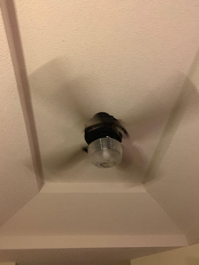 Ceiling fan with light fixture against a textured white ceiling and light beige beams.