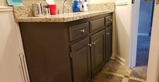 Dark gray bathroom vanity with granite countertop, inside an off-white bathroom.