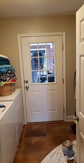 Laundry room with a white door leading outside, laundry machines, and baskets of laundry.