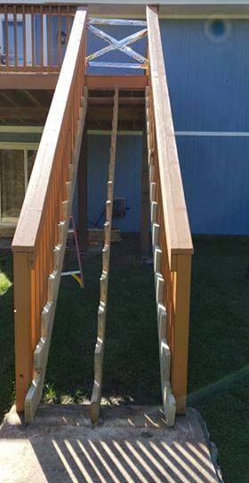 Wooden staircase leading down from a deck, with a central rope, against a blue wall.