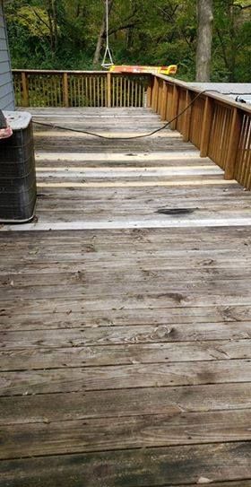 Weathered wooden deck with railing, showing signs of age and disrepair.